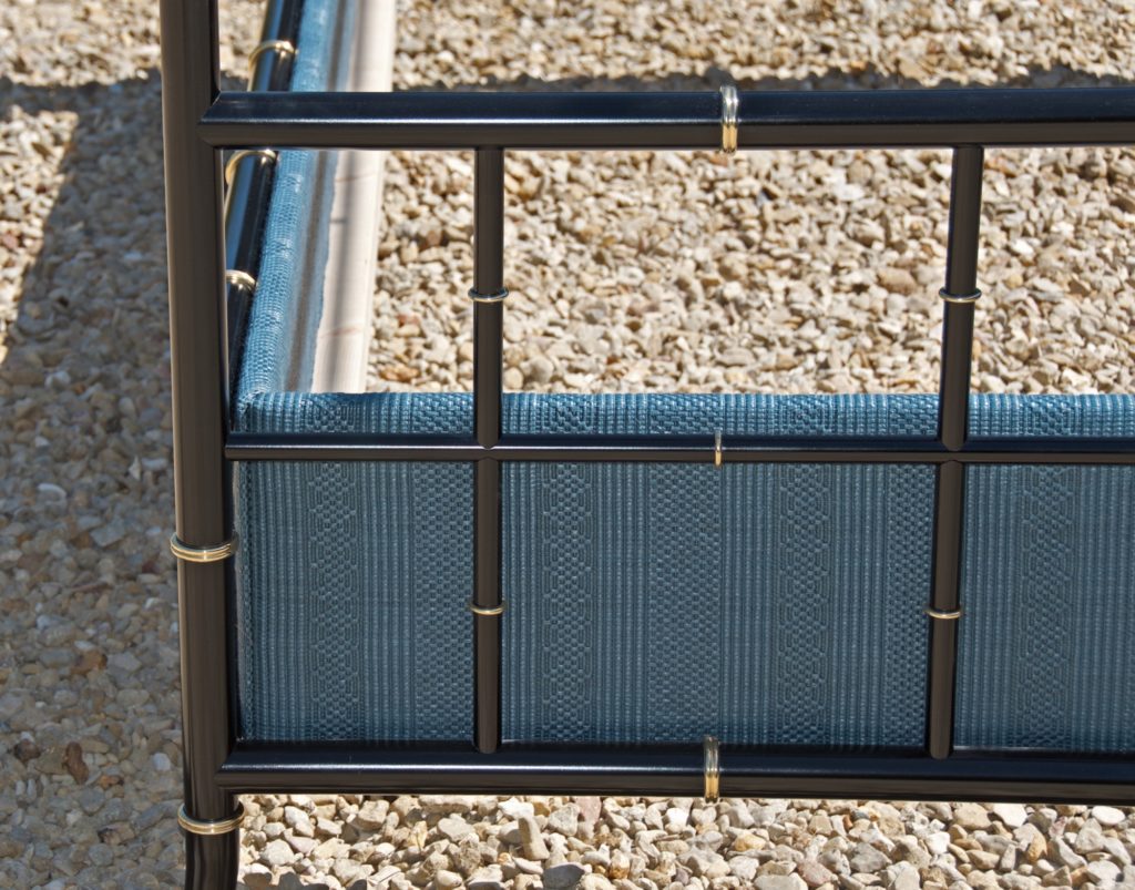 A close-up of a Custom Four-Poster Bed showcases black metal bars and gold accents with a blue upholstered panel.