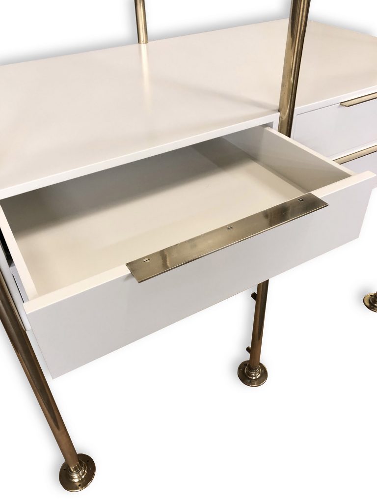 A white drawer is partially open, part of a bespoke dressing room furniture set with a sleek surface and gold-colored legs. The modern metallic handle complements the minimalistic and contemporary design perfectly.