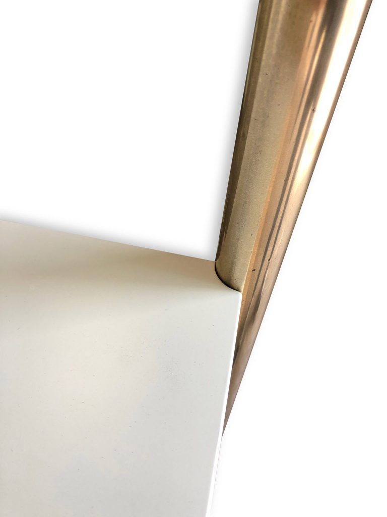 Close-up of a sleek, modern design featuring the corner of a white surface intersected by a brass, metallic diagonal rod—an elegant detail inspired by bespoke dressing room furniture on a white background.