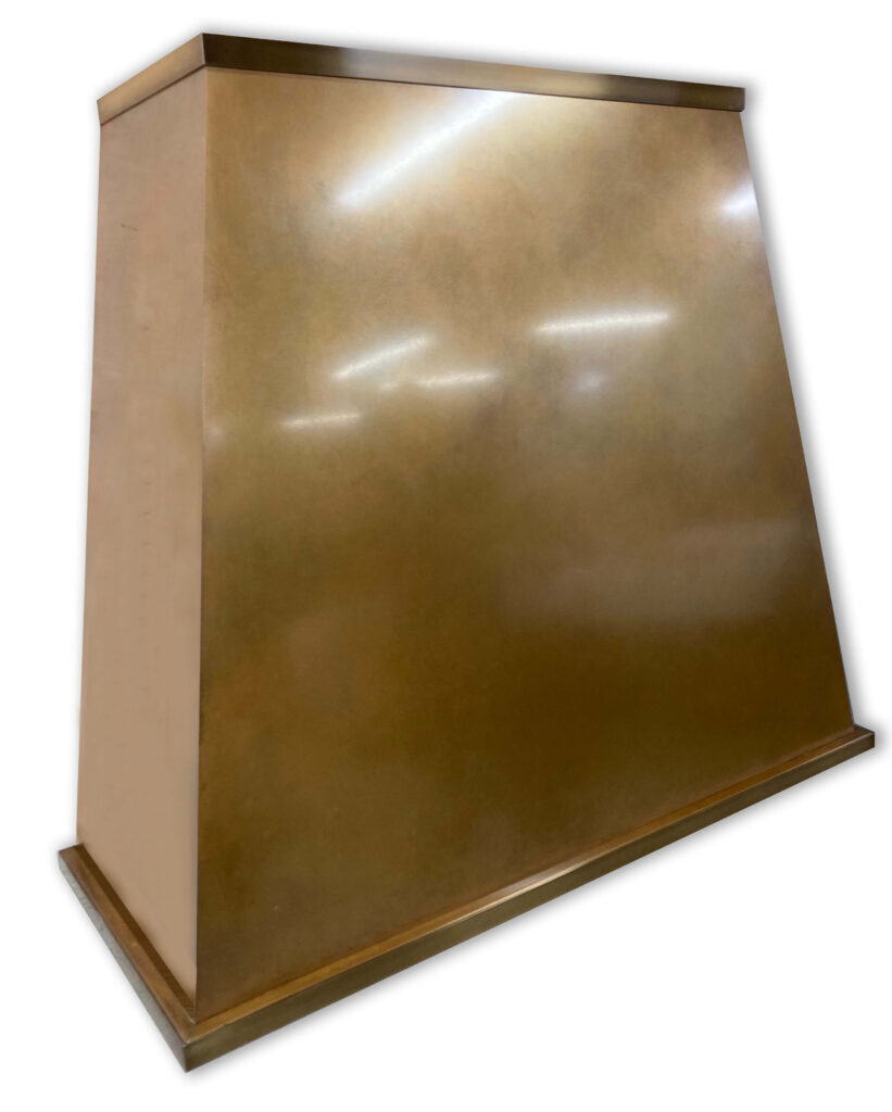 A close-up view of the Handmade Patinated Copper Cooker Hood showcases its smooth, reflective surface with a warm, golden hue. This triangular-shaped hood, featuring a flat, broad base, highlights its metallic allure through masterful craftsmanship using patinated copper.
