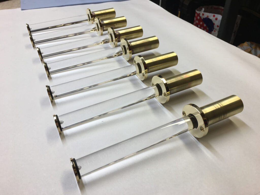 brass and acrylic valet hooks arranged in a row in the workshop showing the transparency of the acrylic rods. The hooks are extended