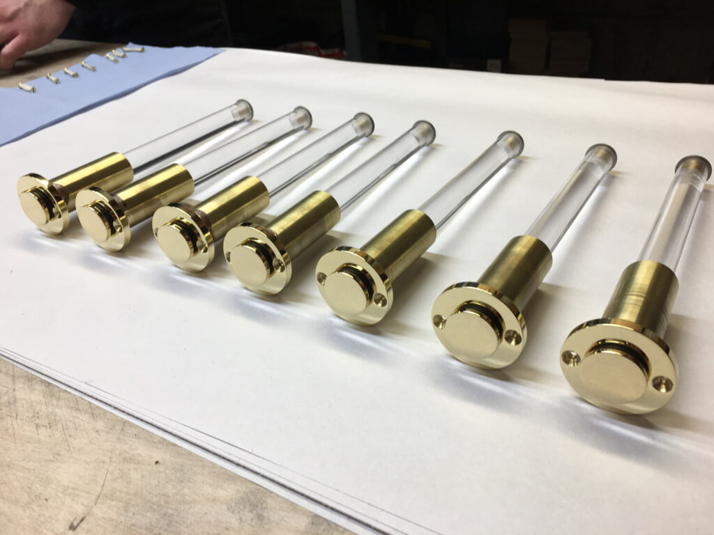 brass and acrylic valet hooks arranged in a row in the workshop showing the transparency of the acrylic rods. The hooks are retracted